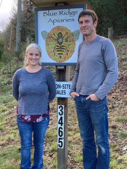 Beekeepers standing in front of business sign