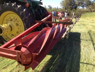 Red rollercrimper attached to a tractor