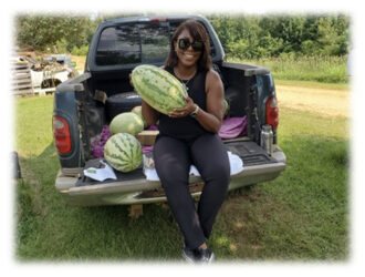 Women on truck tail bed holding watermelon.