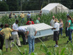 Pastured Poultry house with people gathered around in the field to look at the structure